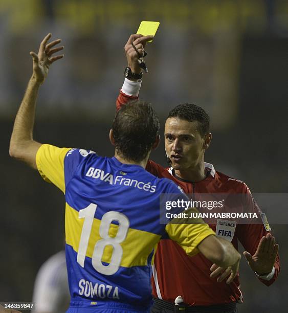Colombian referee Wilmar Roldan shows the yellow card to Boca Juniors midfielder Leandro Somoza during their Copa Libertadores 2012 semifinals first...