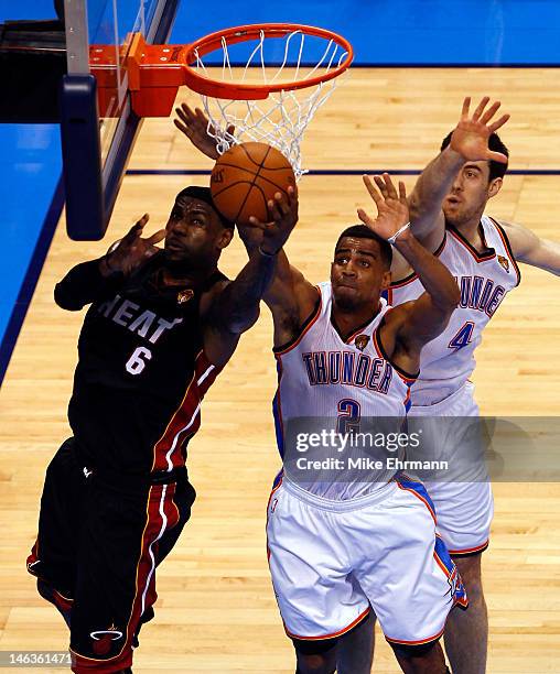 LeBron James of the Miami Heat goes up for a shot against Nick Collison and Thabo Sefolosha of the Oklahoma City Thunder in the first quarter in Game...