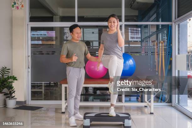 asian male trainer or physiotherapist helping woman to strength training and doing exercises on medical visit at hospital - sports training clinic 個照片及圖片檔