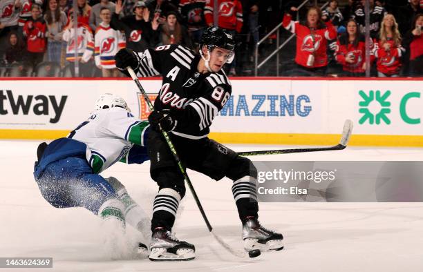 Jack Hughes of the New Jersey Devils takes a shot as Quinn Hughes of the Vancouver Canucks defends in the overtime at Prudential Center on February...