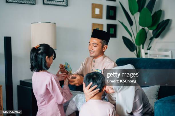 malay muslim kids in traditional costume showing apologize gesture to their parents during aidilfitri celebration malay family at home celebrating hari raya . - eid greeting stock pictures, royalty-free photos & images