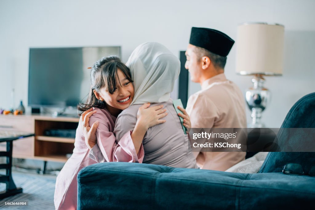 Malay muslim kids in traditional costume showing apologize gesture to their parents during Aidilfitri celebration malay family at home celebrating hari raya .