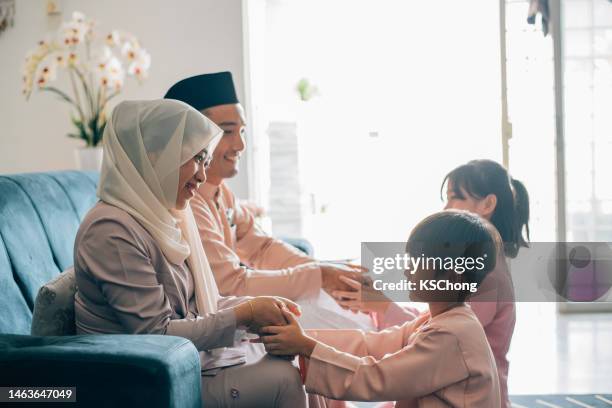 malay muslim kids in traditional costume showing apologize gesture to their parents during aidilfitri celebration malay family at home celebrating hari raya . - malay songkok stock pictures, royalty-free photos & images