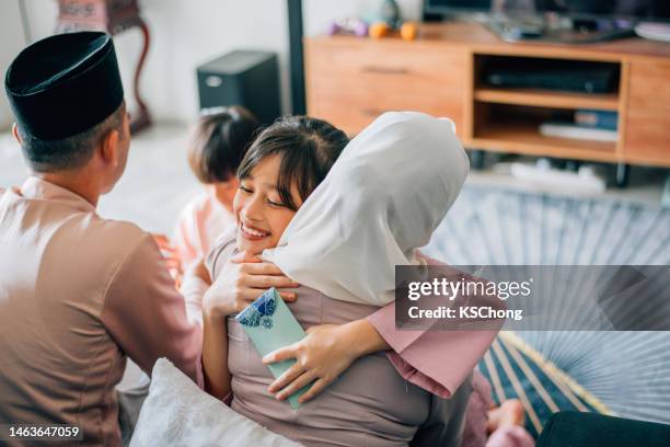 malaiische muslimische kinder in traditioneller tracht zeigen entschuldigungsgeste gegenüber ihren eltern während der aidilfitri-feier malaiische familie zu hause feiern hari raya. - hari raya celebration stock-fotos und bilder