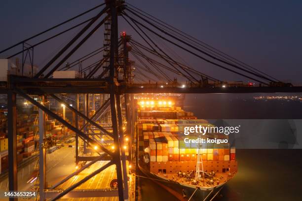 large cargo ship full of containers at night - economic stimulus fotografías e imágenes de stock