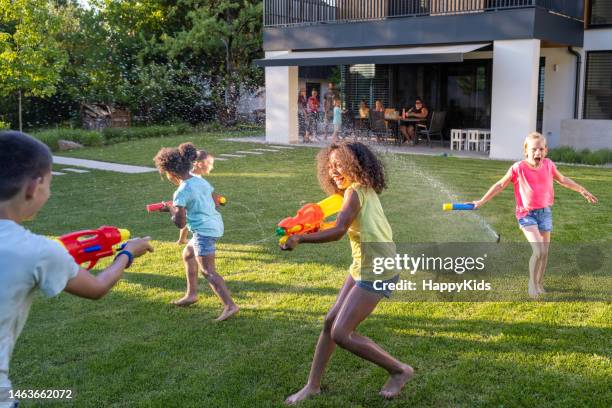 children playing with water guns - house backyard stock pictures, royalty-free photos & images