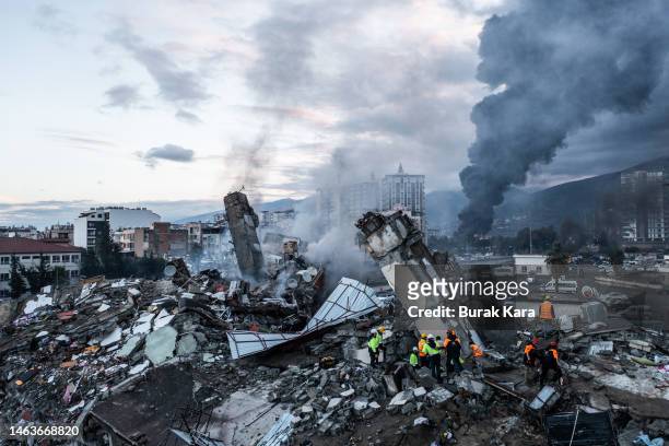 Smoke billows from the Iskenderun Port as rescue workers work at the scene of a collapsed building on February 07, 2023 in Iskenderun, Turkey. A...
