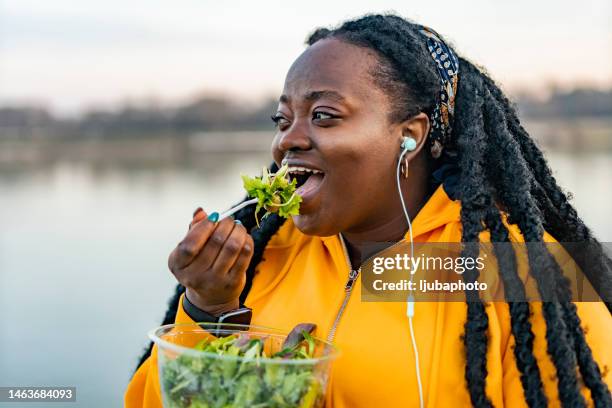 una donna afroamericana che mangia insalata fresca per pranzo - grasso nutrienti foto e immagini stock