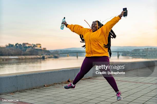 happy overweight woman jumping and enjoying life outdoors. - self-love stock pictures, royalty-free photos & images