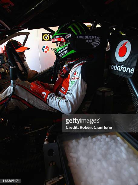Jamie Whincup driver of the Team Vodafone Holden sits in his car as his cool box is topped up with dry ice prior to practice for round six of the V8...