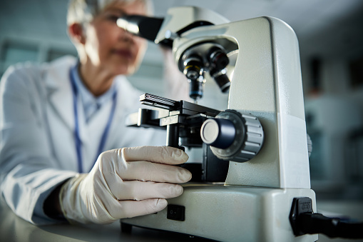 Close up of female scientist working on a microscope in laboratory.