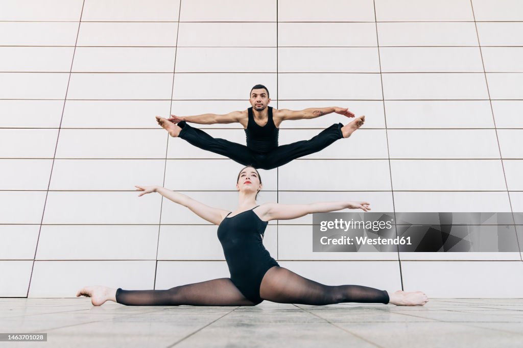 Couple dancing with legs apart in front of wall