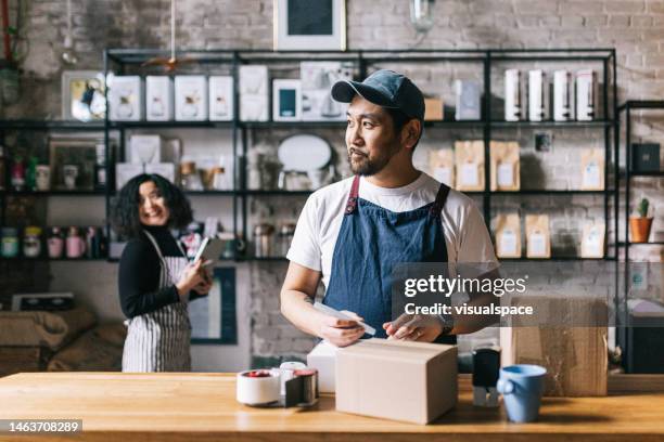 el dueño de la cafetería empaca una caja de su café recién tostado - pequeña empresa fotografías e imágenes de stock