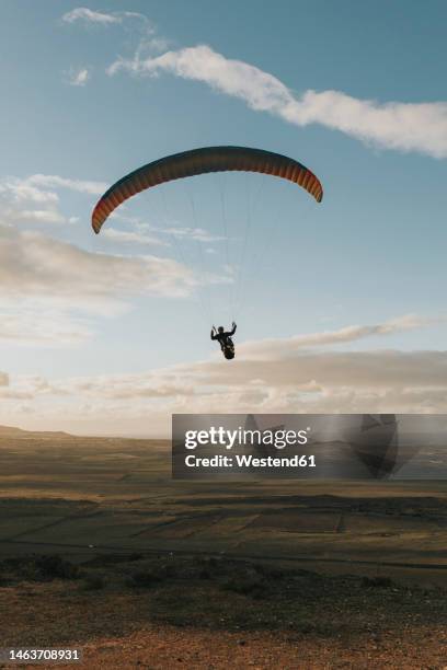 man paragliding under cloudy sky at sunset - plane in sky photos et images de collection