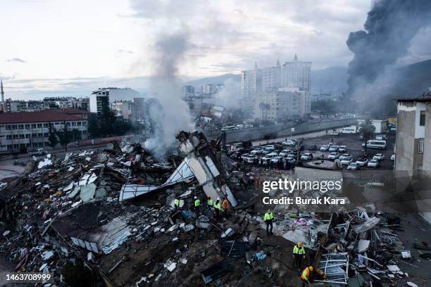 Smoke billows from the Iskenderun Port as rescue workers work at the scene of a collapsed building on February 07, 2023 in Iskenderun, Turkey. A...