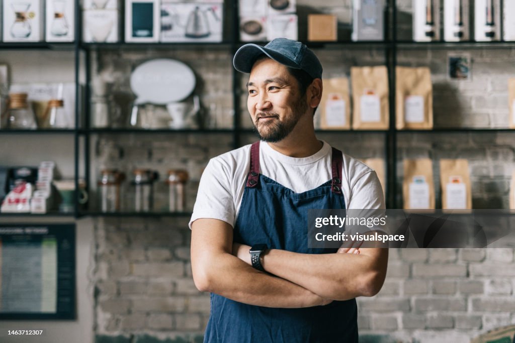 Propietario japonés seguro de pie en su tostadora de café