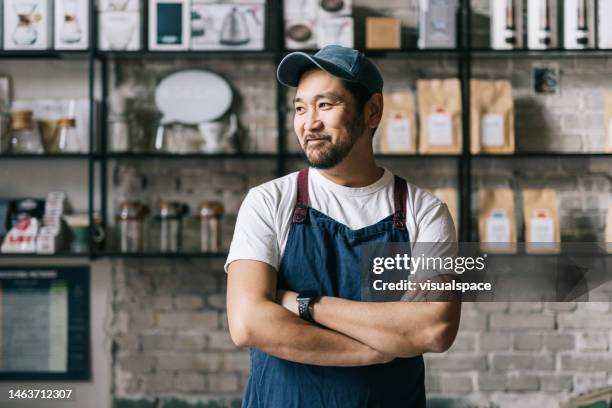 confident japanese owner standing at his coffee roastery - klein bedrijf stockfoto's en -beelden