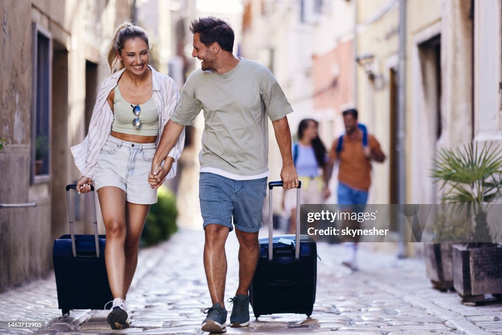 Feliz Pareja De Turistas Arrastrando Sus Maletas Por La Calle Foto de stock  - Getty Images