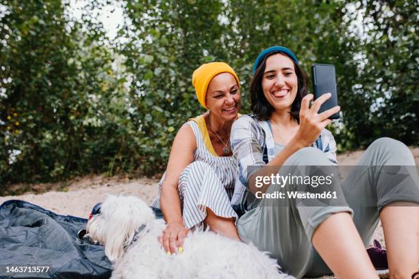 happy women taking selfie through mobile phone at park - diferença entre gerações - fotografias e filmes do acervo