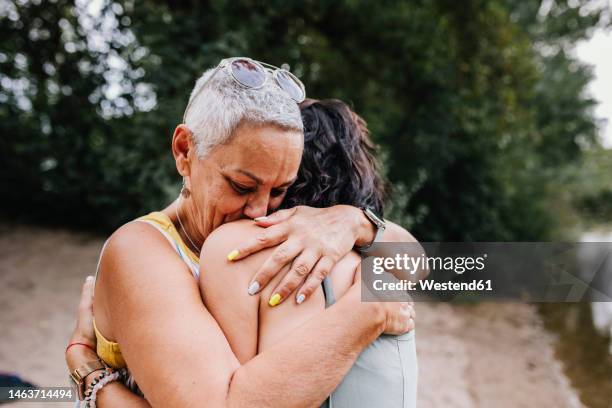affectionate friends hugging each other at park - diferença entre gerações - fotografias e filmes do acervo