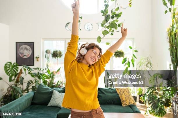 happy young woman wearing headphones dancing at home - 20 years old dancing stock pictures, royalty-free photos & images