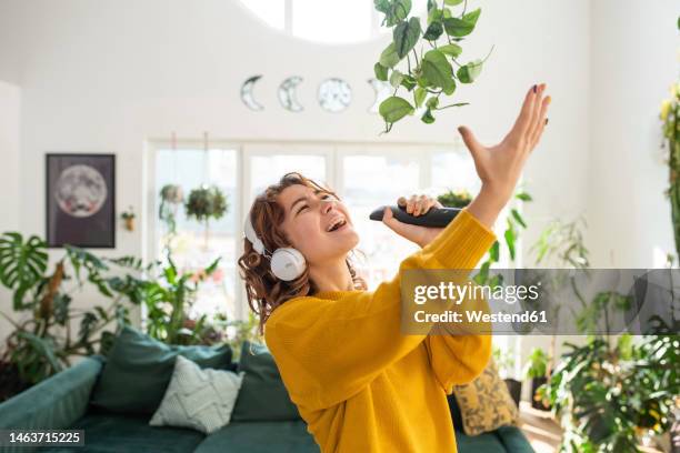 smiling young woman singing in living room at home - women singing stock pictures, royalty-free photos & images