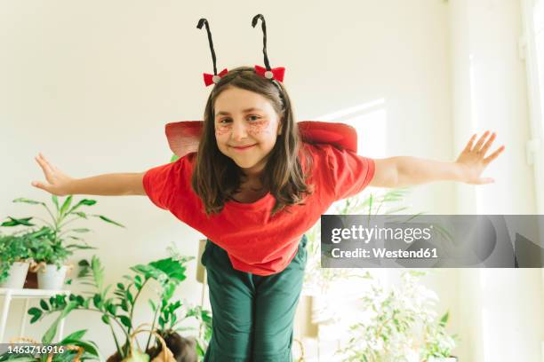 happy girl wearing bug costume standing with arms outstretched at home - pretending to be a plane stock pictures, royalty-free photos & images