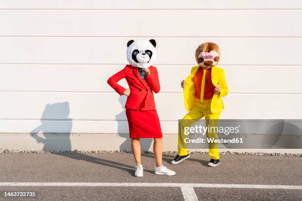 man and woman wearing animal masks standing in front of wall - bear suit stock-fotos und bilder