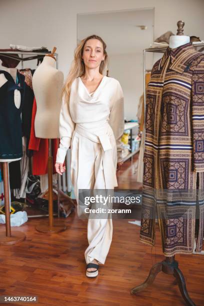 trying on her remodeled jumpsuit at the dressmaker's studio and looking at camera - jumpsuit fashion stock pictures, royalty-free photos & images