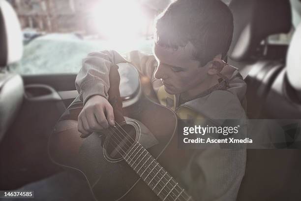 teenage boy plays guitar in rear seat of car - boy playing with cars stock pictures, royalty-free photos & images