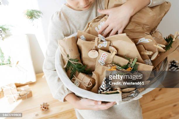 girl holding basket of advent calendar gifts at home - advent calendar surprise imagens e fotografias de stock
