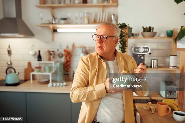 casually clothed senior man having breakfast at his domestic kitchen - senior men eating stock pictures, royalty-free photos & images