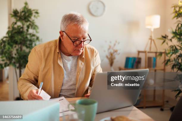 finances, savings, annuity insurance and bills counting taxes at home - senior using laptop stock pictures, royalty-free photos & images