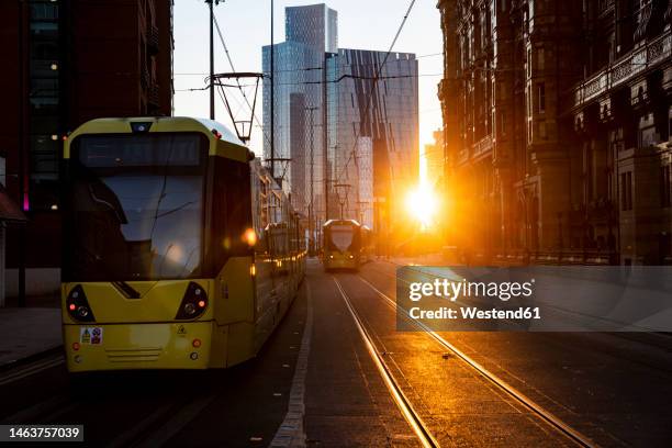 uk, england, manchester, cable cars moving along downtown street at sunset - manchester stock-fotos und bilder