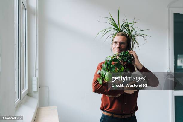 businessman talking on smart phone and standing with plants in front of wall - green economy stock pictures, royalty-free photos & images