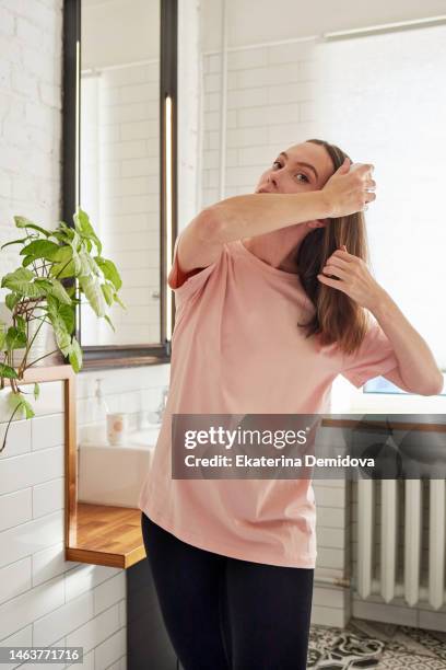 woman combing her t-shirt in bathroom in the morning - thick white women fotografías e imágenes de stock