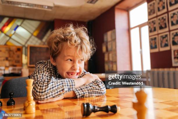 boy sitting at table playing chess in country club - kids playing chess stock pictures, royalty-free photos & images