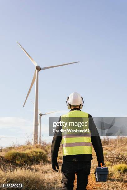 technician with toolbox standing in front of wind turbines on sunny day - energy transition stock pictures, royalty-free photos & images