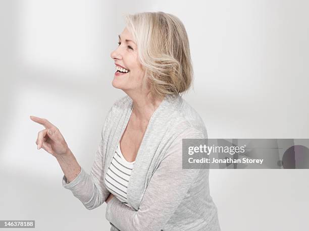 mature woman standing pointing and laughing - point stock pictures, royalty-free photos & images