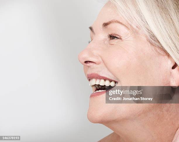side profile shot of mature woman's face laughing - natural portrait studio shot white background stock-fotos und bilder