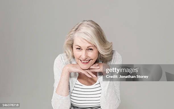 woman resting her chin on her hands smiling - leaning on elbows stock pictures, royalty-free photos & images