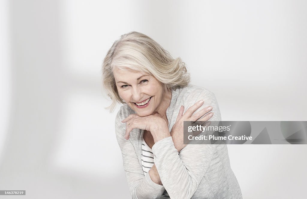 Mature woman with arms resting on hand laughing