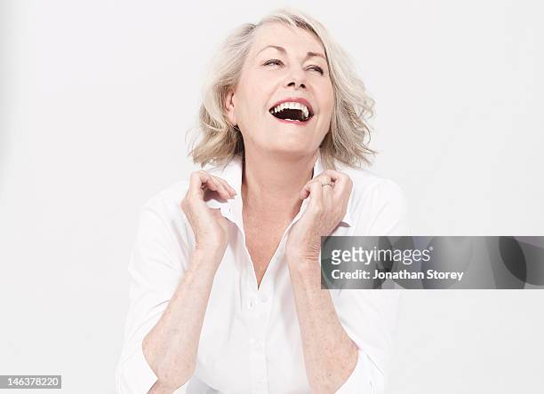 mature woman sitting, touching the collar of shirt - caucasico foto e immagini stock