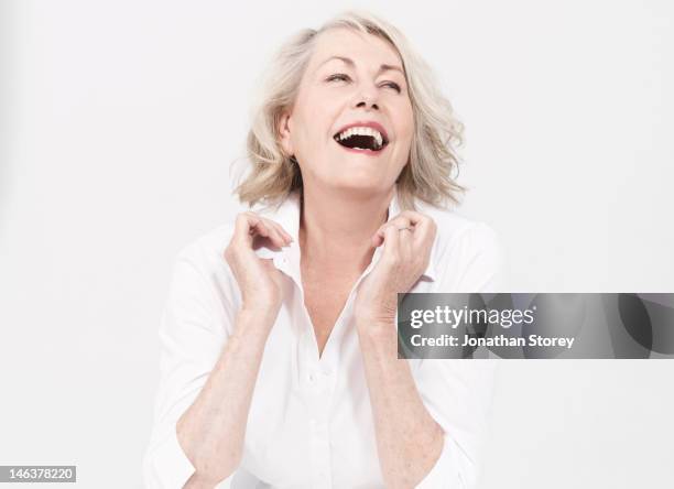 mature woman sitting, touching the collar of shirt - aging skin stock pictures, royalty-free photos & images