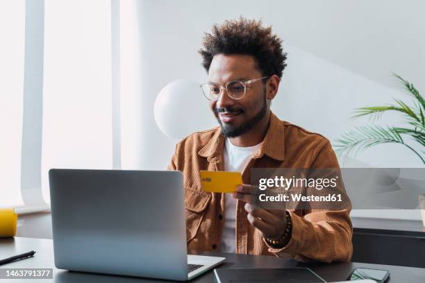 smiling businessman making payment with credit card - mann mit kreditkarte stock-fotos und bilder