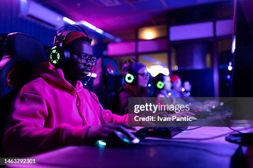 Jogador negro e seus amigos jogando videogames em clube de entretenimento. Jogador negro e seus amigos jogando videogames em clube de entretenimento.