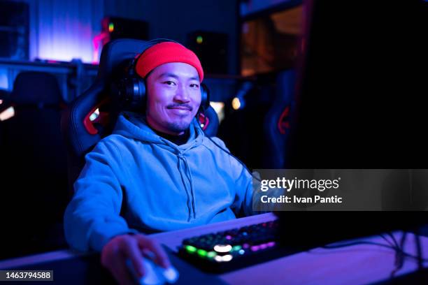 smiling asian man playing esports on pc in gaming club. - game streamer stock pictures, royalty-free photos & images