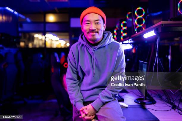 lächelnder chinesischer männlicher spieler genießt im gaming-club. - computerspieler stock-fotos und bilder