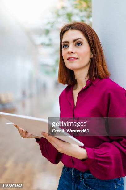 thoughtful businesswoman holding digital tablet - lila stockfoto's en -beelden