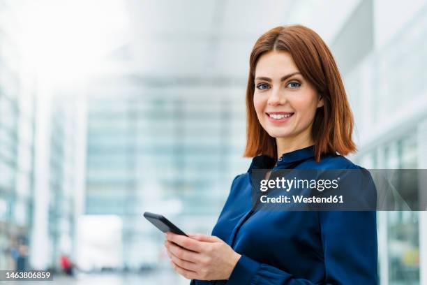 smiling businesswoman holding mobile phone - blue blouse stock pictures, royalty-free photos & images